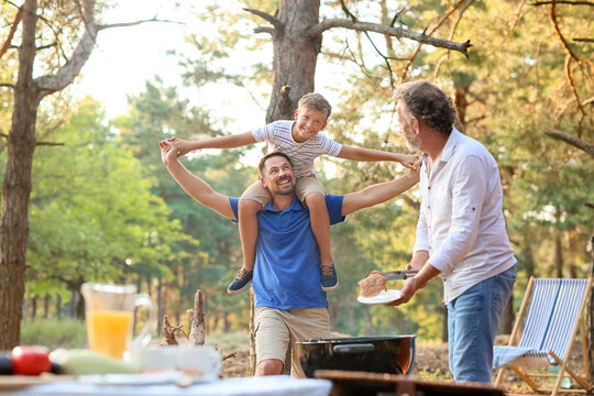 Little boy having fun with his father at barbecue party on summer day