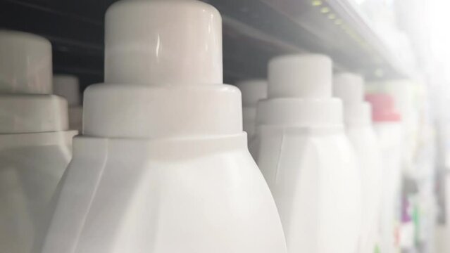Liquid detergent for clothes in plastic bottles line up on the supermarket shelf. Close-up shot