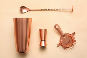 Cobbler shaker, double jigger, strainer and mixing spoon on color background