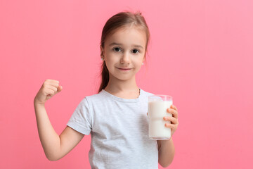 Cute little girl holding glass of milk and showing muscles on color background