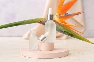 Composition with bottles of essential oil and strelitzia flower on light background