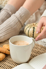 Woman drinking tasty pumpkin coffee on floor in room