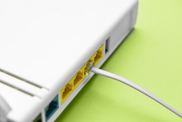 Modern wi-fi router and internet cable on green background, closeup