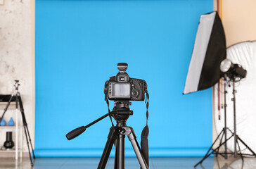 Modern camera with tripod in photo studio