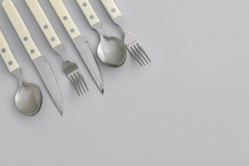 Set of stainless steel cutlery with plastic handle on light background, closeup
