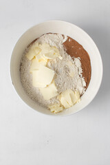 Making pastry dough  in a white bowl, butter, flour, sugar and cinnamon in a bowl