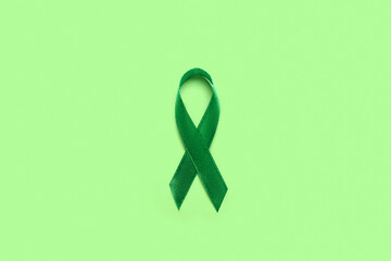 Green ribbon on color background. Liver cancer concept