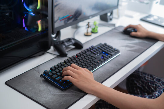 selective focus of a teenager's hands playing on a gaming computer, with a black keyboard on a large gray mouse pad, video game addiction problem
