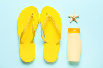 Bottle of sunscreen with flip flops and starfish on blue background - obrazy, fototapety, plakaty