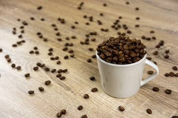 Roasted coffee beans, fragrant, in a coffee mug, on the wooden table in warm colors. For background work, bakery, coffee shop.