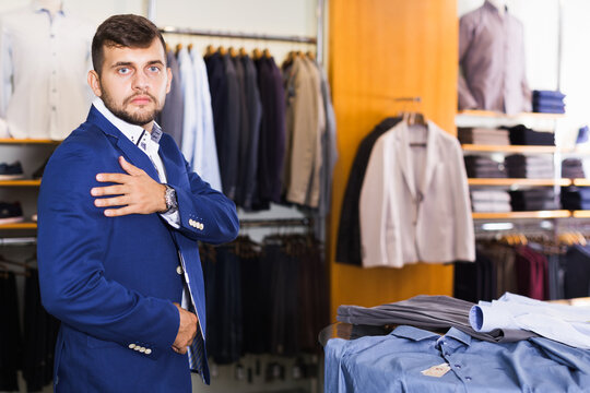 young guy shows off his jacket at a men's store