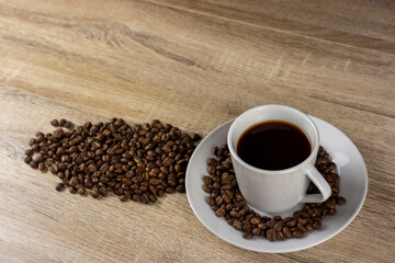 Coffee mug on saucer placed on the table with roasted coffee beans fragrant for background coffee articles.