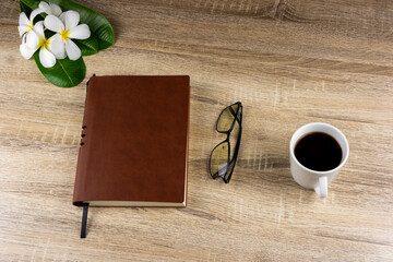 Top view of laptop, notebook, glasses, coffee mug on wooden table for concept work from home, To-do list, Business home.
