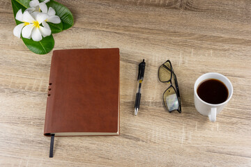 Top view of laptop, notebook, glasses, coffee mug on wooden table for concept work from home, To-do list, Business home.