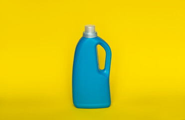 Softener in blue plastic bottle isolated on yellow background. Bottle with liquid laundry...