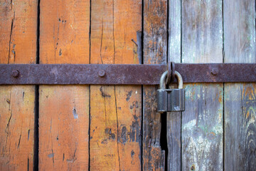 closeup big lock on rustic wooden door orange and grey.