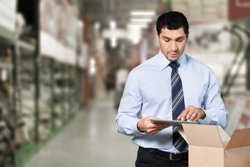 Portrait of engineer foreman order details checking goods and supplies on shelves with goods background in warehouse. logistic and business export