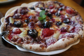 eating blue barry Pizza on the wooden plate close-up with pizzacutter