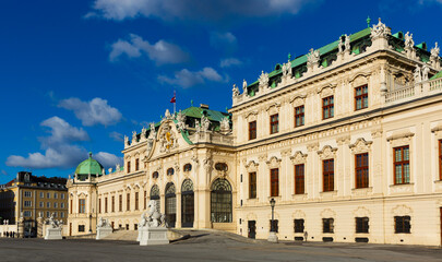 Fototapeta na wymiar Scenic view of main facade and entrance of baroque building of upper Belvedere palace with large staircase and various sculptures on sunny day, Vienna, Austria