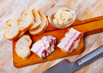 Traditional Russian and Ukrainian food, salted smoked pork bacon with horseradish on a wooden background