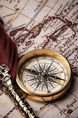 Old feather pen and golden compass on the antique mundi map.