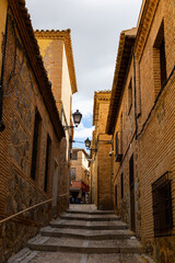 Typical narrow winding streets paved with cobblestones in old district of Spanish city of Toledo in spring..