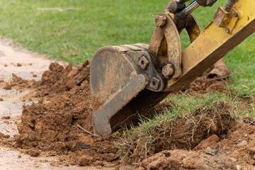Excavator bucket with earth on asphalt. Excavation. Excavations with an excavator.