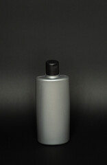 Black shampoo packaging mockup. Vertical empty plastic cosmetic package for man, isolated on black background. Container of conditioner, hair rinse.