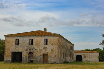 Fototapeta na wymiar Ancient abandoned farmhouse in the Tuscan countryside near Bolgheri, Italy. Ruin with warehouse and barn