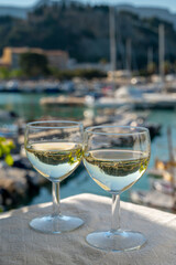 Two glasses of white wine from Cassis region served on outdoor terrace with view on old fisherman's harbour with colourful boats in Cassis, Provence, France