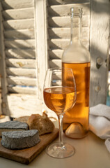 Cold rose wine in glass and bottle served with goat cheeses on outdoor terrace with view on old fisherman's harbour with colourful boats in Cassis, Provence, France