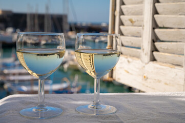 Two glasses of white wine from Cassis region served on outdoor terrace with view on old fisherman's...