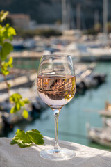 Rose wine in glass served on outdoor terrace with view on old fisherman's harbour with colourful boats in Cassis, Provence, France