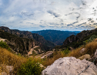 Fototapeta na wymiar panoramic of beautiful canyon with cloudscape and mountains with rural way in guachochi chihuahua 