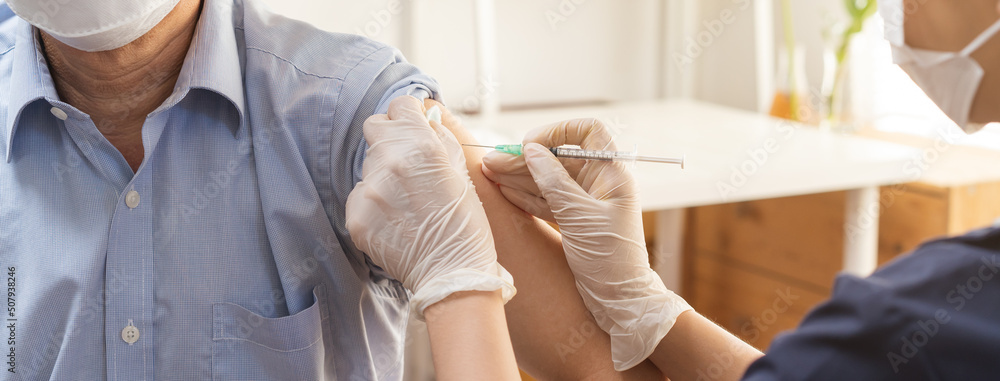 Wall mural Covid-19,coronavirus, elderly asian adult man getting vaccine from doctor or nurse giving shot to mature patient at clinic. Healthcare, immunization, disease prevention against flu or virus pandemic.