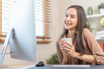 Freshness, beautiful asian young business woman holding cup coffee or drinking, freelancer working on PC compute sitting her house.Technology, social distance of work from home, office in covid-19.