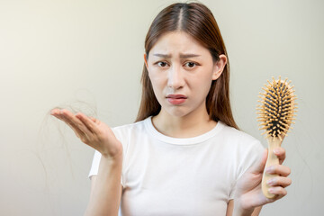 Serious, worried asian young woman, girl holding comb, show her hairbrush with long loss hair...