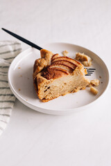 A slice of an apple cake served in a white plate.