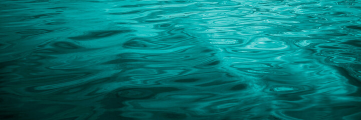 Blue-green water background. Reflection of light on the wavy surface of the water. Ripples....