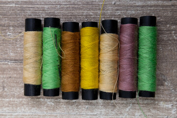 sewing threads of various colors arranged on a desk, work tool for sewing, wallpaper with detail in the texture