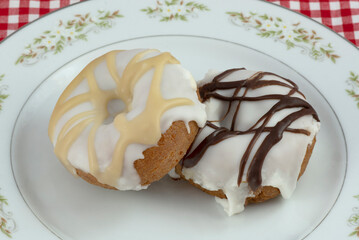 Two doughnuts with white icing and caramel and chocolate topping on plate