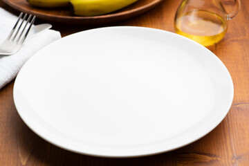 木目のテーブルの上に何もない空の白色の皿とコピースペースの背景素材