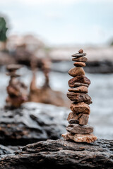 Concept of balance and harmony. Cairn stack of stones pebbles cairn on coast amid the crashing waves. Meditative art of stone stacking