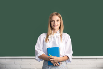 High school student holding book near blackboard, learning english or mathematics in class.