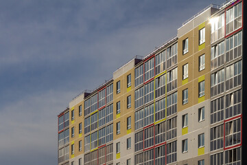 A modern multi-storey panel house in Russia is painted in bright colors against the sky