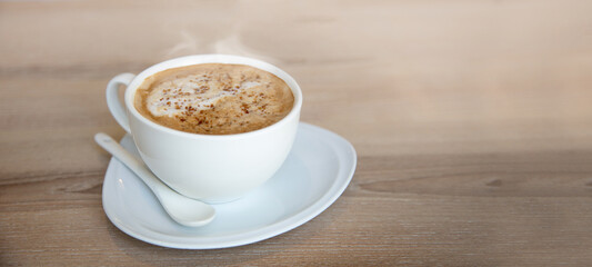 coffee cup on wood table with blur outdoor cafe.