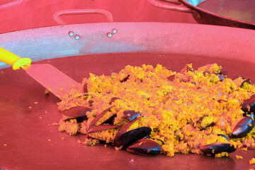 Spanish dish called PAELLA with rice cooked with seafood and mussels in the large pan with a RED...