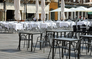 empty chairs and tables without customers in the outdoor bar of the square during the economic crisis caused by the coronavirus lockdowns in the city square