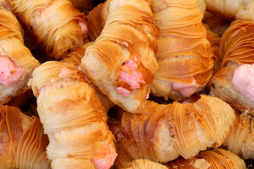 background of cannoli-shaped pastries with pink strawberry and raspberry flavored custard