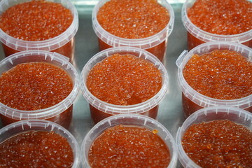 Almaty, Kazakhstan - 03.25.2022 : Sale of red caviar in plastic containers on the market.